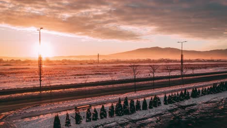 Sunrise-behind-a-snowy-mountain-with-an-open-road-inside,-Drone-4K