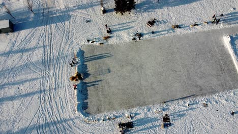 winter-aerial-rise-twist-over-residential-detached-homes-at-empty-manmade-ice-rink-connected-to-skating-track-double-oval-of-where-people-practice-skating-at-community-roadside-park-hay-stack-cube-2-3