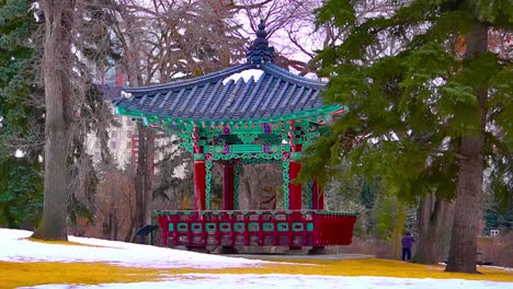 Government-House-property-centered-look-at-Korean-Pavillion-gazebo-on-winter-cloudy-afternoon-with-forest-trees-in-the-background-while-a-silhouette-person-in-the-far-background-taking-pictures