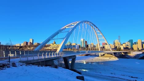 4k-Perfect-Loop-Winter-Time-Lapse-twilight-white-modern-Walter-Dale-bridge-North-traffic-view-on-a-clear-blue-sky-sunny-afternoon-with-city-skyline-in-the-horizon-refkection-on-icy-melting-river