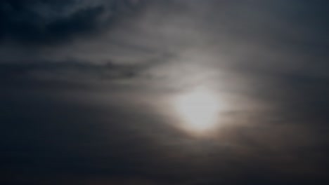 4k-time-lapse-of-twilight-sunset-surrounded-by-light-clouds-turning-into-darkness-as-the-sun-sets-downwards-behind-the-vapour-silky-sheer-rolling-change-in-the-sky