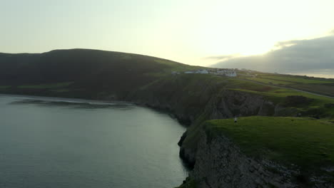 Drone-footage-of-a-person-walking-towards-cliff-edge-at-Rhossili-bay-in-Gower,-South-Wales