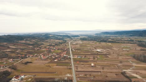 Eine-Freie-Straße-Zwischen-Zwei-Dörfern,-Die-Zu-Den-Bergen-Führt,-Drohne-4k-Farbig