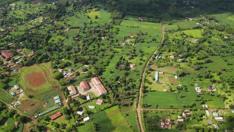 Vista-Aérea,-Pequeña-Ciudad-De-Kenia-En-El-Paisaje-Del-Valle-Verde-Bajo-El-Parque-Nacional-Del-Monte-Kilimanjaro,-Disparo-De-Drones-De-60-Fps