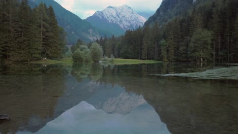Alpine-mountain-range-reflecting-in-lake-Plansar-or-Plansarsko-jezero-in-Jezersko,-Slovenia-in-autumn,-fast-pan-left-to-right
