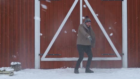 Man-dodging-snowballs-in-slow-motion-near-a-red-house-in-Norway