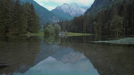 Alpine-mountain-range-reflecting-in-lake-Plansar-or-Plansarsko-jezero-in-Jezersko,-Slovenia-in-autumn,-slow-panning-left-to-right