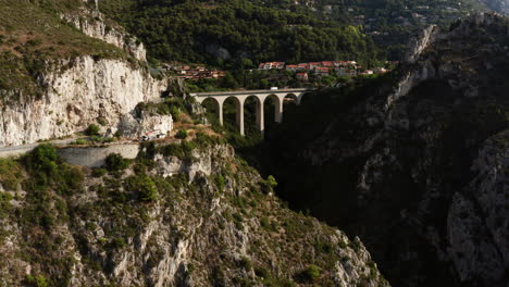 Aerial-forward-showing-roads-in-mountain-and-gigantic-bridge-with-driving-vehicles-in-background-during-sunny-day