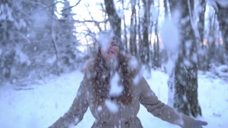Beautiful-caucasian-girl-throwing-snow-in-the-air-in-winter-forest,-SLOMO