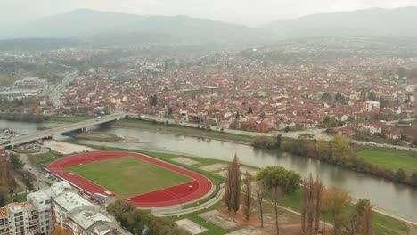 Campo-Atlético-En-El-Terraplén-Del-Río-Ibar-En-Kraljevo,-Serbia-Con-Tráfico-En-La-Ruta-Europea-E761