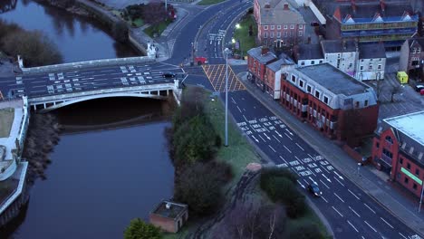 Aerial-view-looking-down-city-centre-canal-roundabout-infrastructure-suburban-streets-traffic-at-daybreak-slow-rise