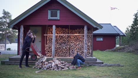Couple-Collecting-Firewoods-In-Front-Of-The-Red-Cabin