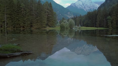 Alpine-mountain-range-reflecting-in-lake-Plansar-or-Plansarsko-jezero-in-Jezersko,-Slovenia-in-autumn,-panning-shot
