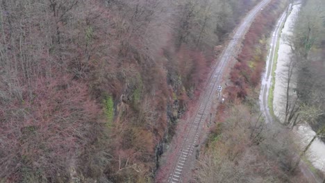 Aerial-drone-shot-of-Bocq-river-with-train-track-in-the-forest-in-the-province-of-Namur,-Belgium