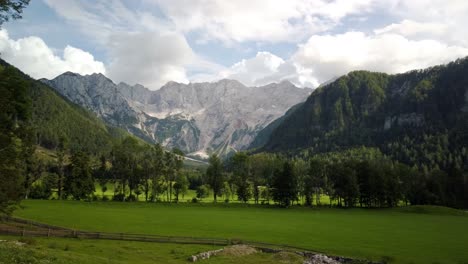 Alpine-valley,-Jezersko,-Slovenia,-clouds-above-mountains-and-meadows-with-trees-in-front