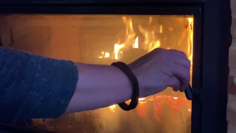 Close-shot-of-a-fireplace-with-the-hand-of-a-woman-closing-the-protection-glass