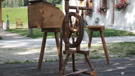 Vintage-wooden-spinning-wheel,-traditional-Alpine-house-in-background