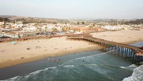 People-on-Pismo-beach-beside-wooden-pier,-California