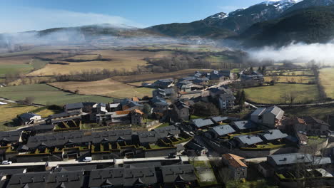 Luftaufnahme-Des-Kleinen-Dorfes-Bor-In-La-Cerdanya,-Mit-Den-Schneebedeckten-Bergen-Im-Hintergrund