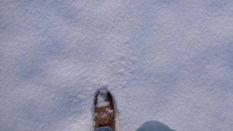 POV-close-up-of-boots-walking-through-thick-fresh-powdery-snow-in-slow-motion-on-a-sunny-winter-day-in-Bavaria,-Germany