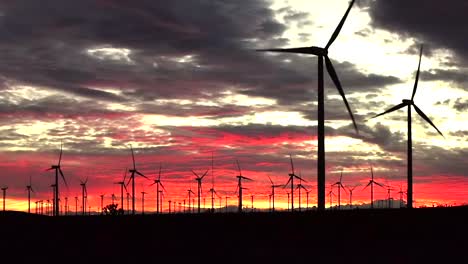 Field-of-Wind-Turbines-at-sunset,-beautiful-red-sky-color,-green-renewable-energy
