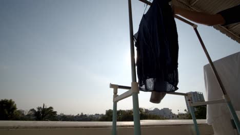 A-person-hangs-laundry-to-dry-on-his-apartment-balcony-on-a-sunny-day---isolated-low-angle-view
