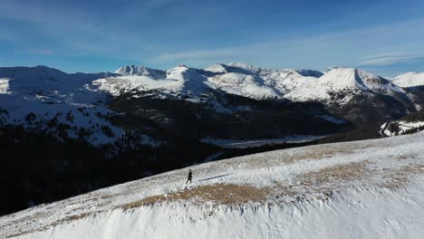 Aerial-View-of-Female-Person-Walking-Uphill-in-Beautiful-Snowy-Winter-Landscape-of-Rocky-Mountain-Range,-North-America