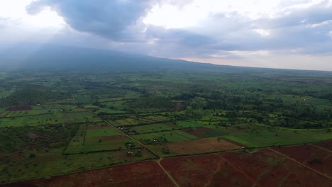 Aerial-drone-view-overlooking-green-fields-and-farms,-in-a-rural-Kenya,-Africa