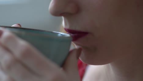 Close-up-of-Lady-with-lipstick-drinking-coffee-out-of-beautiful-blue-cup