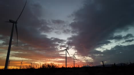 Time-lapse-of-wind-turbines-turning-at-sunset,-global-warming-climate-change