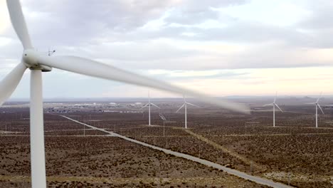 Closeup-propeller-blades-reveal-into-aerial-shot-across-vast-wind-turbine-farm-landscape-aerial-dolly-left