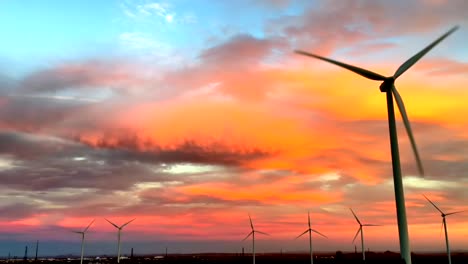 Green-energy-wind-turbine-blades-rotate-against-dramatic-orange-sunset-sky