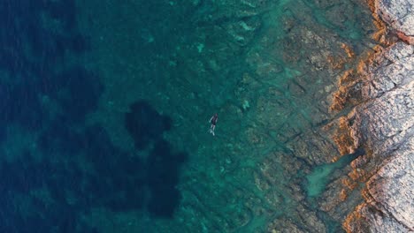 Hombre-Buceando-En-El-Mar-Turquesa-Prístino-Con-Corales-Y-Rocas-Saludables