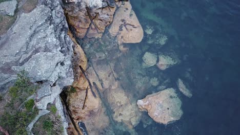Rocks-at-the-bottom-of-a-mountain-cliff-at-Balmoral-Beach,-Sydney---Top-view