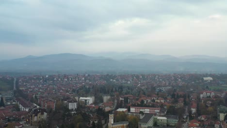 Aerial-pedestal-shot-of-the-skyline-of-Kraljevo,-Serbia-on-a-cloudy-foggy-day