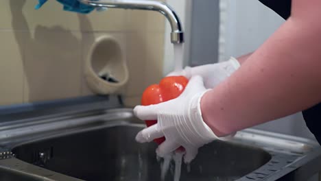 Red-paprika-is-washed-under-running-water-with-disposable-gloves