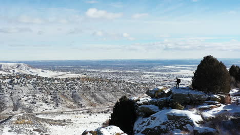 Luftaufnahme-Einer-Einsamen-Person,-Die-Auf-Einem-Hügel-Steht,-Mit-Herrlichem-Blick-Auf-Die-Winterlandschaft-Der-Felsigen-Bergkette,-Colorado-Usa