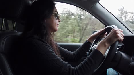 Hispanic-woman-driving-car-on-road-through-countryside,-road-trip