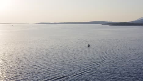 Erstaunliche-Landschaftsansicht-Aus-Der-Luft-über-Ein-Segelboot,-Das-Bei-Sonnenuntergang-Durch-Den-Ozean-Fährt