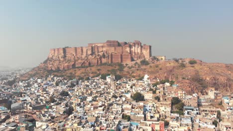 Aerial-footage-of-a-large-palace-on-top-of-a-hill-above-the-vast-city-of-Jodhpur,-India