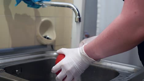 Red-paprika-is-washed-under-running-water-with-disposable-gloves