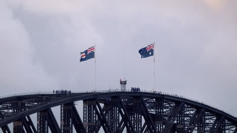 Australische-Und-New-South-Wales-Flagge-Weht-Im-Wind-Mit-Bergsteigern-Auf-Der-Hafenbrücke-Von-Sydney-In-Australien