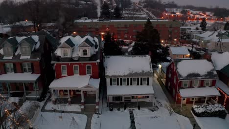 Traditional-two-story-colonial-homes-covered-in-winter-snow,-decorated-with-Christmas-holiday-lights