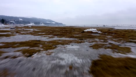 Drone-speeding-over-the-frozen-Saint-Lawrence-river-before-moving-up-in-Charlevoix