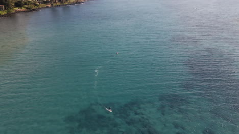 Surfer-on-electric-surfboard-speeding-on-wide-azure-ocean-water,-Maui,-Hawaii