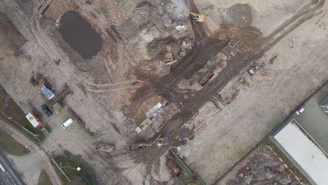 High-top-down-aerial-of-excavators-collecting-rubble-from-demolished-building-on-construction-site