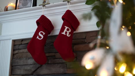 Christmas-stocking-hanging-above-the-fireplace-for-Santa-Claus-to-fill---sliding-view-with-the-decorated-tree-in-the-foreground