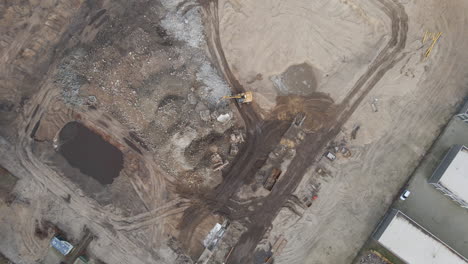 Top-down-aerial-of-excavators-collecting-rubble-from-demolished-building-on-construction-site