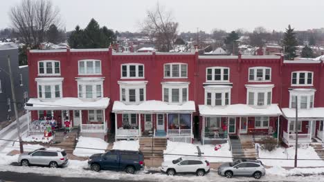 Red-rowhomes-covered-in-snow,-decorated-for-winter-Christmas-holiday