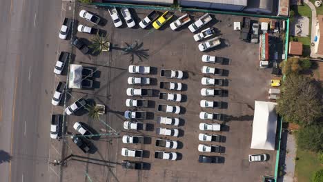 Aerial-bird's-eye-descending-spiral-shot-of-trucks-lined-up-at-a-used-automotive-dealership-lot
